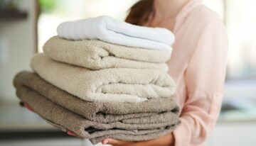 Fresh laundry. Shot of a young woman carrying a pile of folded towels